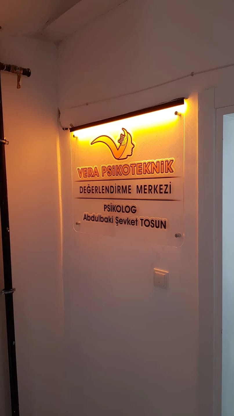 Merkez içinde duvara asılı, sıcak ışıkla aydınlatılmış Vera Psikoteknik tabelası